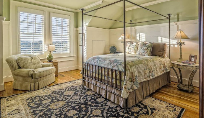 well-lit bedroom with a clean blue ornate area rug placed on a wooden floor