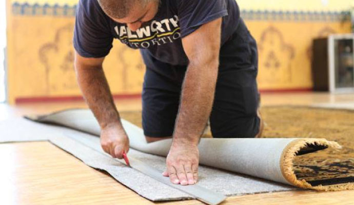 Person cutting rug pad with a utility knife.