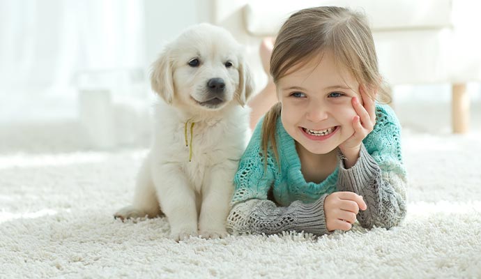 Puppy and child laying down on a clean rug