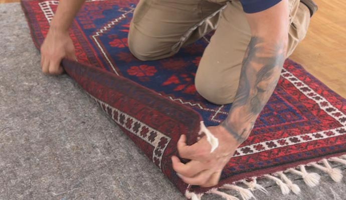 Person placing a rug on a rug pad