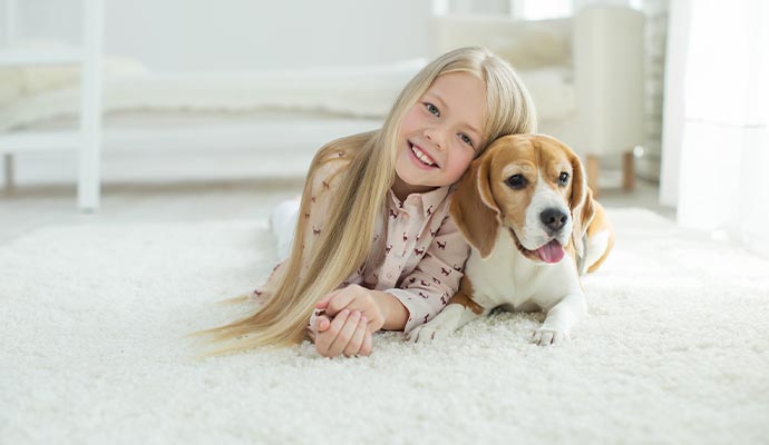 A puppy and a child laying on a rug