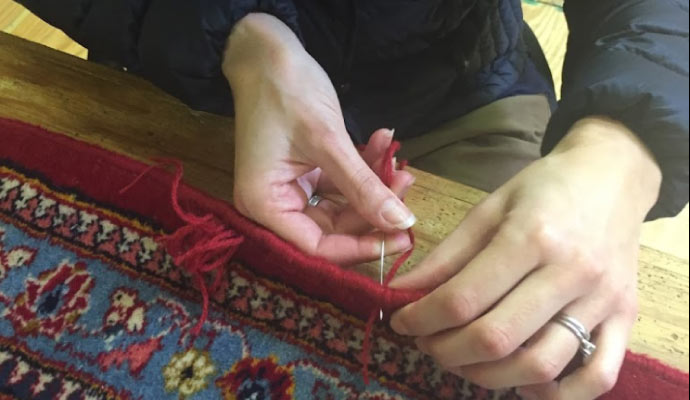 Expert repairing rug fringe.